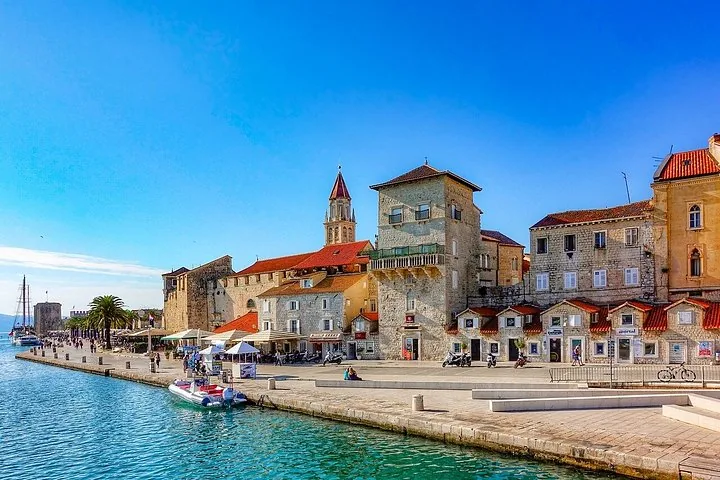 Uferpromenade in Trogir mit historischen Steingebäuden und Booten.