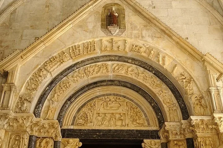 Intricate stone carvings above an arched doorway of a historic building.